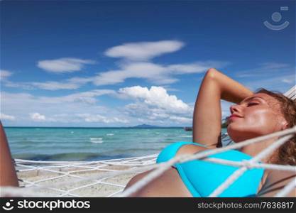 Girl in bikini relaxing in hammock on the beautiful paradise beach. Girl relaxing in hammock