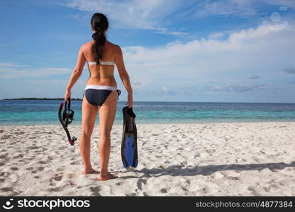 Girl in bikini with snorkeling gear on the beach Maldives.