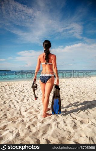 Girl in bikini with snorkeling gear on the beach Maldives.