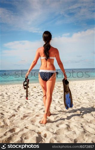 Girl in bikini with snorkeling gear on the beach Maldives.
