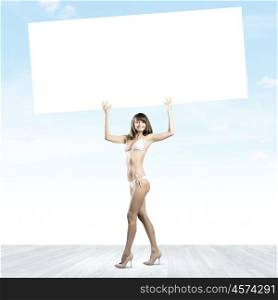 Girl in bikini. Young attractive girl holding white blank banner above head