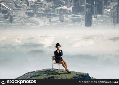Girl in black cylinder. Pretty girl wearing retro hat siting on chair