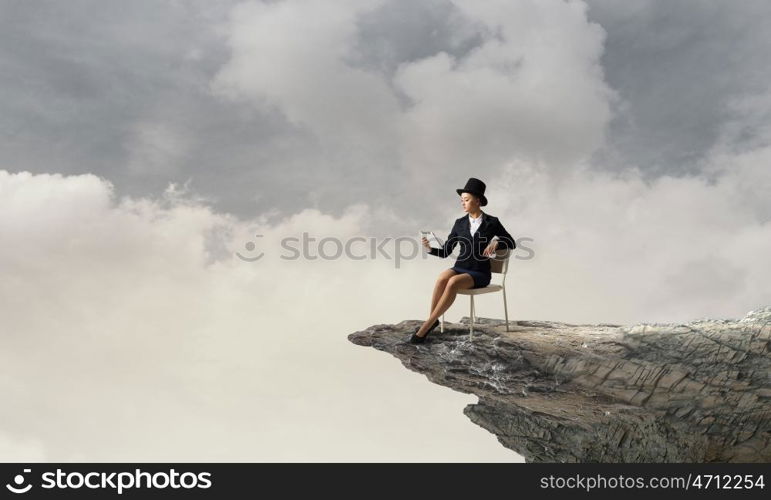 Girl in black cylinder. Pretty girl wearing retro hat siting on chair with tablet in hand