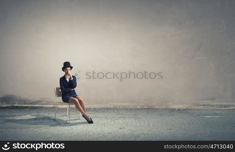 Girl in black cylinder. Pretty girl wearing retro hat siting on chair