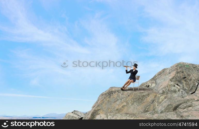 Girl in black cylinder. Pretty girl wearing retro hat siting on chair and looking in spyglass