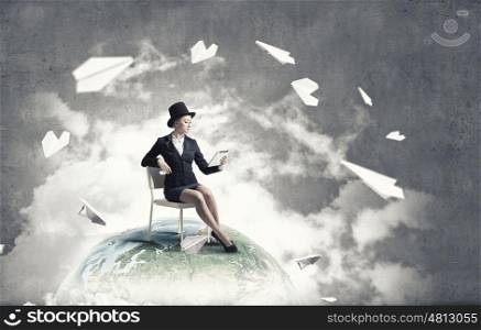 Girl in black cylinder. Pretty girl wearing retro hat siting on chair with tablet in hand. Elements of this image are furnished by NASA