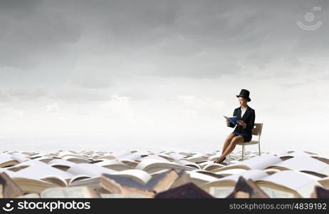 Girl in black cylinder. Pretty girl wearing retro hat siting on chair with book in hands