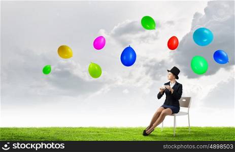 Girl in black cylinder. Pretty girl wearing retro hat siting on chair with cup in hand