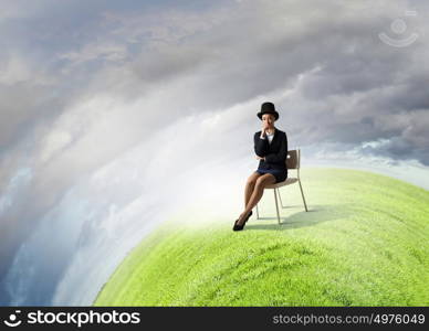 Girl in black cylinder. Pretty girl wearing retro hat siting on chair