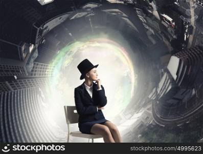 Girl in black cylinder. Pretty girl wearing retro hat siting on chair