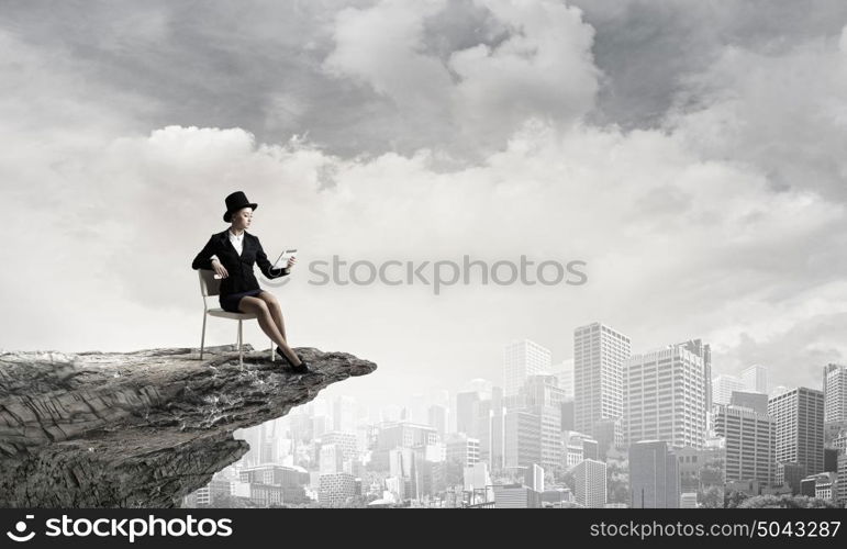 Girl in black cylinder. Pretty girl wearing retro hat siting on chair with tablet in hand