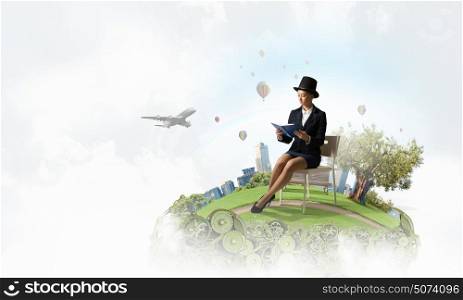 Girl in black cylinder. Pretty girl wearing retro hat siting on chair with book in hands
