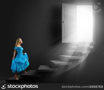 Girl in blue dress. Young blond woman in blue dress walking up the stairs