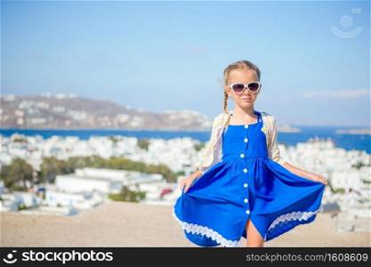 Girl in blue dresses having fun outdoors on Mykonos streets. Adorable little girl at old street of typical greek traditional village