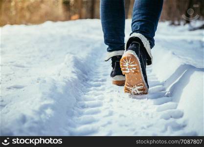 Girl in blue jeans is hiking in the wintertime, legs and shoes