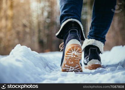 Girl in blue jeans is hiking in the wintertime, legs and shoes
