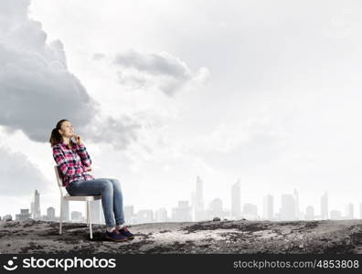 Girl in chair. Young girl sitting in chair against city background