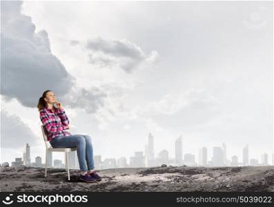Girl in chair. Young girl sitting in chair against city background