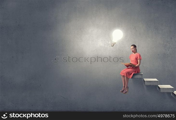 Girl in dress read book. Young attractive woman sitting on top and reading book