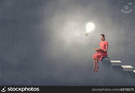 Girl in dress read book. Young attractive woman sitting on top and reading book