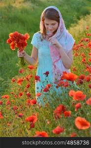 girl in field of poppies in summer sunset