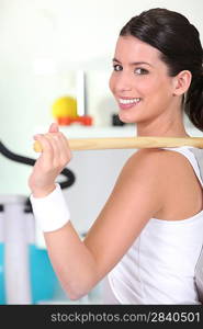 Girl in gym using wooden pole