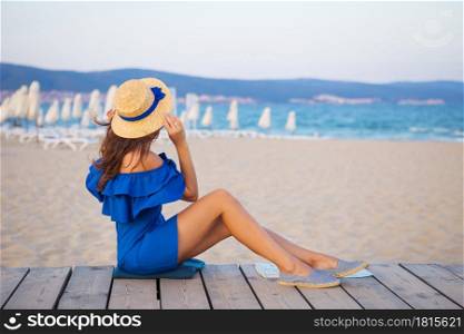 girl in hat and blue dress sitting on a sandy beach, picnic.. girl in hat and blue dress sitting on a sandy beach, picnic