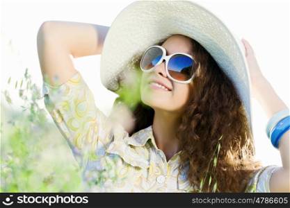 Girl in hat. Young beautiful girl in hat and glasses sitting in grass