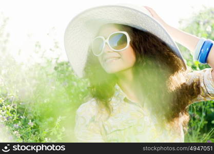 Girl in hat. Young beautiful girl in hat and glasses sitting in grass