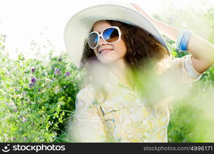 Girl in hat. Young beautiful girl in hat and glasses sitting in grass