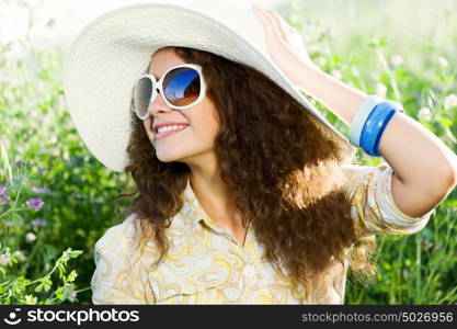 Girl in hat. Young beautiful girl in hat and glasses sitting in grass