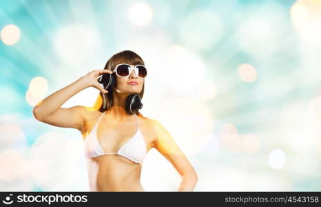 Girl in headphones. Young attractive girl in bikini wearing headphones touching media icon