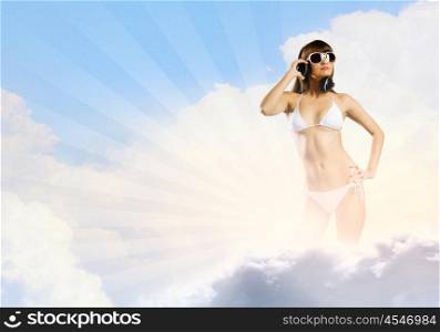Girl in headphones. Young attractive girl in bikini wearing headphones touching media icon