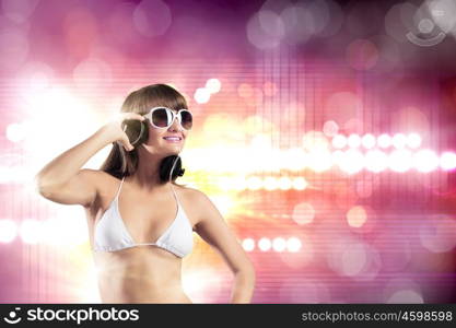 Girl in headphones. Young attractive girl in bikini wearing headphones touching media icon