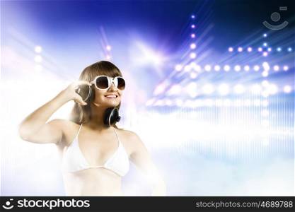Girl in headphones. Young attractive girl in bikini wearing headphones touching media icon