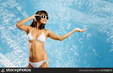 Girl in headphones. Young attractive girl in bikini wearing headphones touching media icon