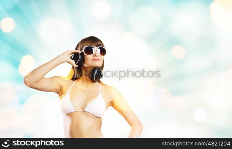 Girl in headphones. Young attractive girl in bikini wearing headphones touching media icon