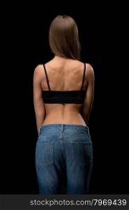 Girl in jeans with naked back relief. Isolate on black.
