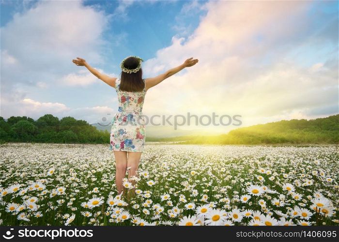 Girl in meadow of camomile spring flower reach hands to the sun. Happy emotional religion and conceptual scene.