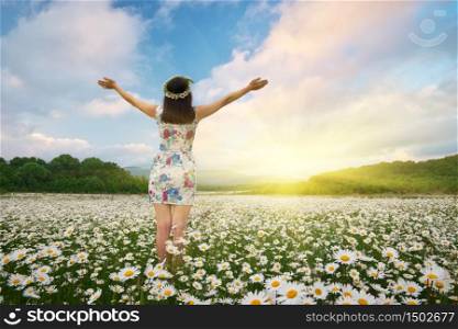 Girl in meadow of camomile spring flower reach hands to the sun. Happy emotional religion and conceptual scene.