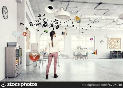 Girl in office interior mixed media. Young woman in modern office interior reaching hand to touch item