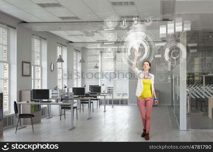 Girl in office interior mixed media. Young woman in modern office interior reaching hand to touch item