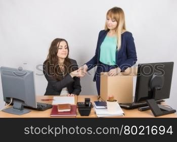 Girl in office standing with a smile in front of the box and shakes hands with a colleague