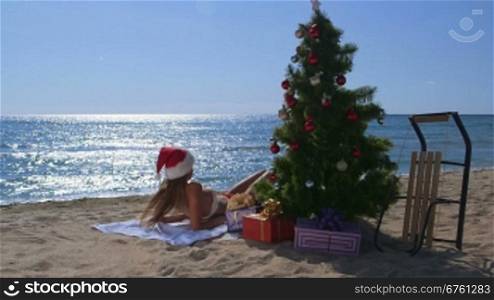 Girl in red Santa hat enjoying Christmas vacation time on tropical beach resort long shot