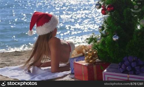 Girl in red Santa hat enjoying Christmas vacation time on tropical beach resort medium shot