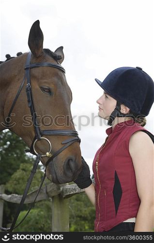 Girl in riding hat holding horse