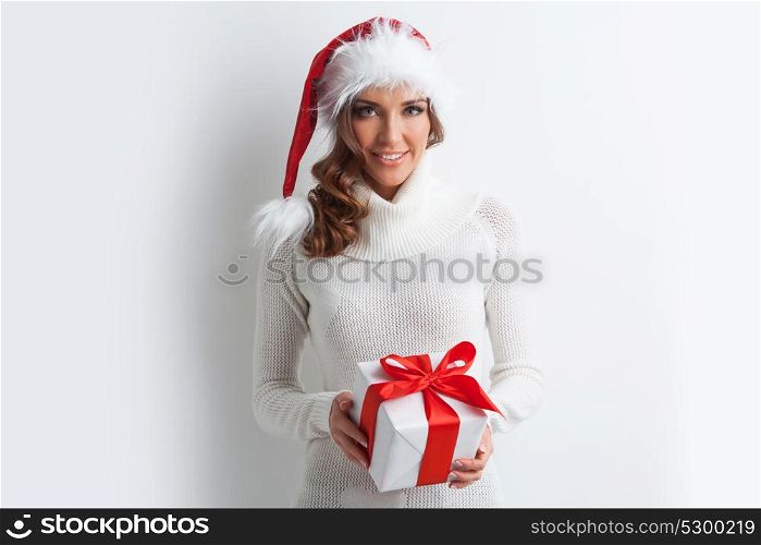Girl in Santa hat holding gift box. Cute laughing girl in Santa hat holding the gift box