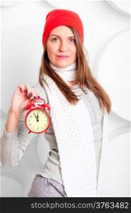 girl in scarf and hat shows the time on the alarm clock