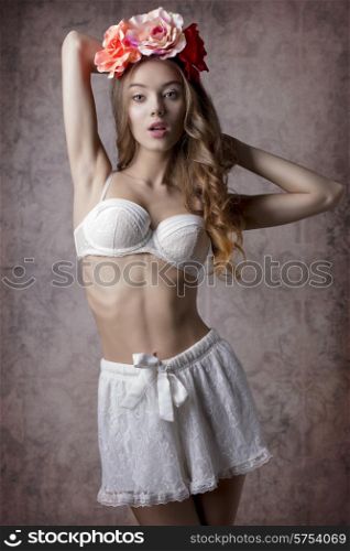 girl in sensual pose with spring flowers on the head and vintage lingerie, natural make-up and long wavy hair. Romantic atmosphere