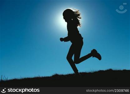 Girl in silhouettes runs with the sun behind her face